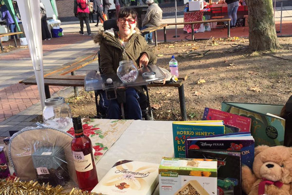 PALS service user running a tobola stall. She is in charge of the money on the stall.